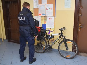 Policjant dokonuje oględzin zabezpieczonego roweru.