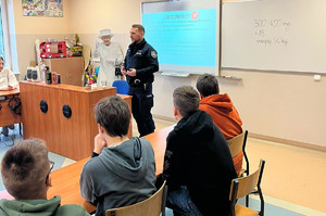 Policjant w klasie szkolnej mówi do uczniów