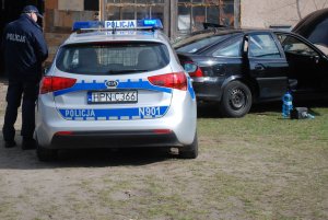 policjant przy radiowozie obserwuje kontrolowany pojazd
