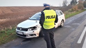 Policjant sporządza oględziny pojazdu.