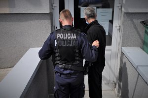 Policjant prowadzi podejrzanego.