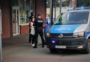 Policyjny radiowóz, w tle policjanci.