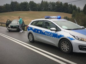 Policyjny radiowóz w tle rozbity samochód.