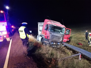 Na zdjęciu policjant wykonujący oględziny pojazdu ciężarowego leżącego w rowie