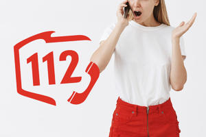 Zdenerwowana kobieta dzwoni na numer alarmowy. Obok logo 112.